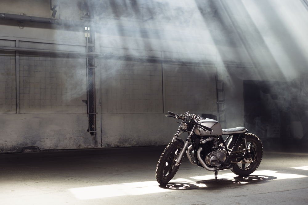 Vintage,Motorcycle,Standing,In,A,Dark,Building,In,The,Rays